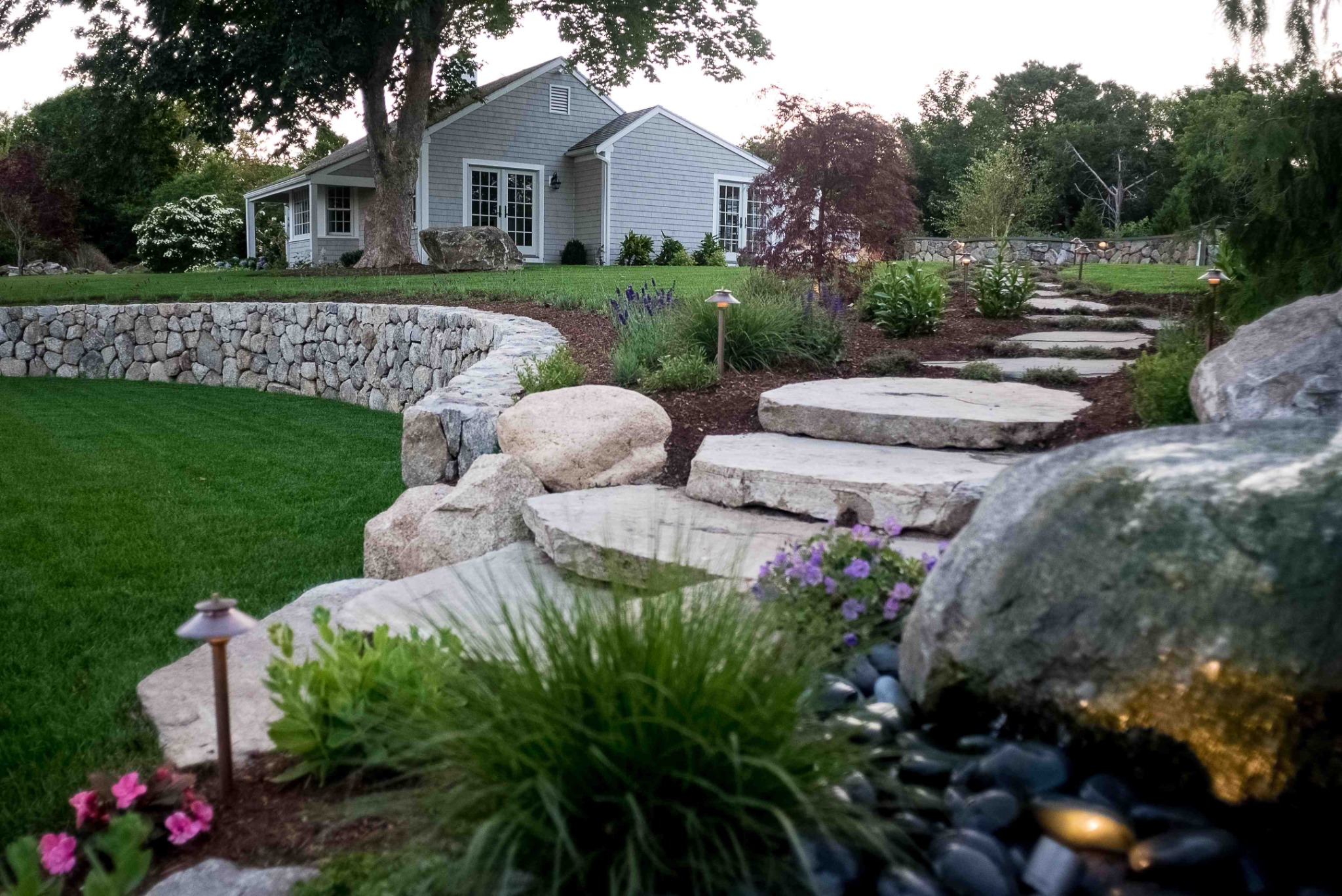 Residential landscape with stone walkway, steps and mature planting
